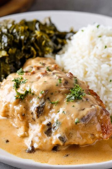 The Best Smothered Chicken Recipe 1 Smothered Chicken Recipe A serving of smothered chicken on a plate, topped with a creamy, flavorful sauce, served alongside a portion of fluffy white rice and cooked greens. The dish looks comforting and full of flavor.