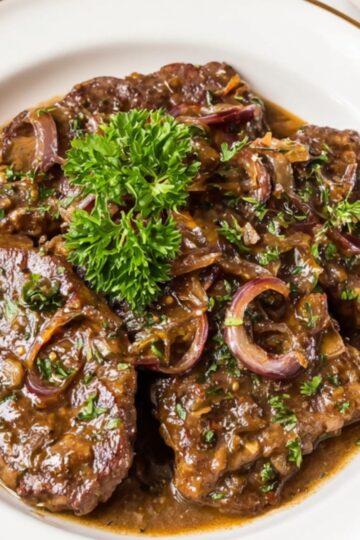 Healthy Smothered Cube Steak Recipe 1 Smothered Cube Steak A perfectly plated dish of smothered cube steak, garnished with fresh parsley, with a side of bread and scattered herbs