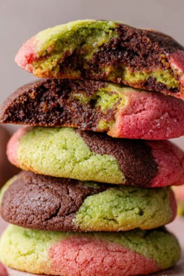 Easy Spumoni Cookies Recipe 3 Spumoni Cookies A stack of freshly baked spumoni cookies with vibrant colors of green pistachio, red cherry, and dark chocolate. The cookies are dusted with sugar and one is broken in half, revealing the interior filled with the marbled dough.