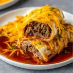 Taco Bell Enchirito A close-up of a hearty, filled enchilada, cut in half to reveal the savory ground beef filling, topped with shredded cheddar cheese and drenched in flavorful enchilada sauce