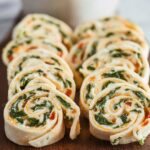Turkey Pinwheels Sliced turkey pinwheels: "The turkey pinwheels are neatly sliced and arranged on a wooden board, revealing their vibrant layers of spinach, turkey, and creamy cheese filling.