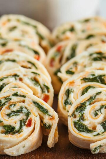 Easy Homemade Turkey Pinwheels Recipe 2 Turkey Pinwheels Sliced turkey pinwheels: "The turkey pinwheels are neatly sliced and arranged on a wooden board, revealing their vibrant layers of spinach, turkey, and creamy cheese filling.