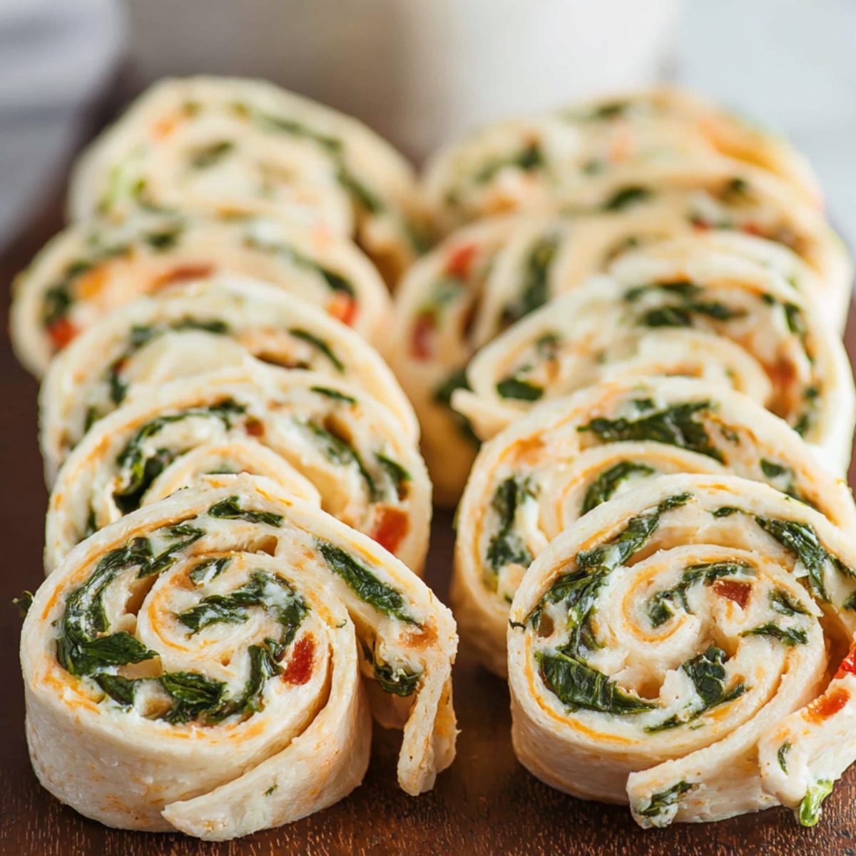 Turkey Pinwheels Sliced turkey pinwheels: "The turkey pinwheels are neatly sliced and arranged on a wooden board, revealing their vibrant layers of spinach, turkey, and creamy cheese filling.