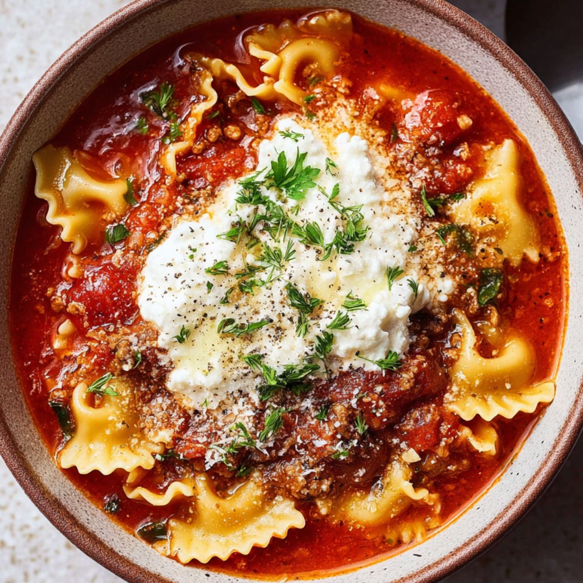 Delicious Vegan Lasagna Soup Recipe 9 Vegan Lasagna Soup A bowl of vegan lasagna soup topped with ricotta, fresh herbs, and sprinkled with parmesan.