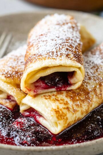 Healthy Homemade Blintzes Recipe 2 blintzes Recipe A delicious serving of blintzes, filled with a sweet or savory mixture, dusted with powdered sugar, and resting on a plate with berry sauce underneath.