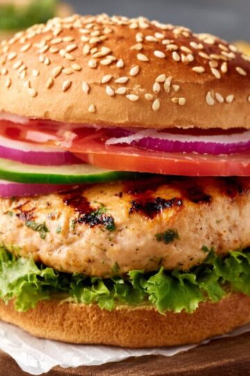 Delicious Grilled Chicken Burgers Recipe 3 chicken burgers is assembled with a grilled chicken patty, fresh vegetables such as lettuce, tomato, and red onion, and placed in a sesame seed bun, ready to serve.