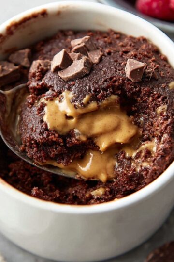 The Best Chocolate Mug Cake Recipe 3 chocolate mug cake A spoonful of soft, fluffy chocolate mug cake with peanut butter in the center, served with fresh raspberries and chocolate chunks on the side