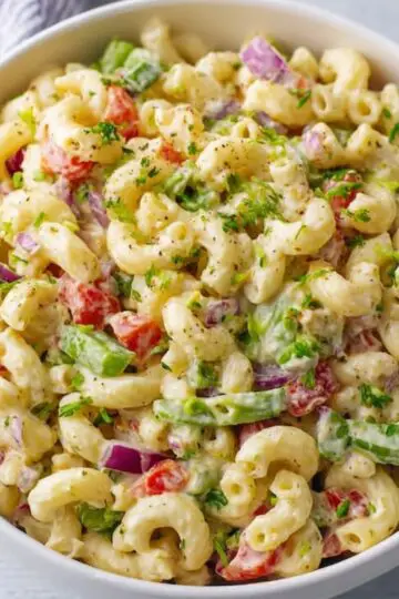 macaroni salad A vibrant bowl of macaroni salad, filled with fresh vegetables like red bell peppers, onions, and celery, all mixed with creamy dressing. This classic side dish is perfect for gatherings and picnics