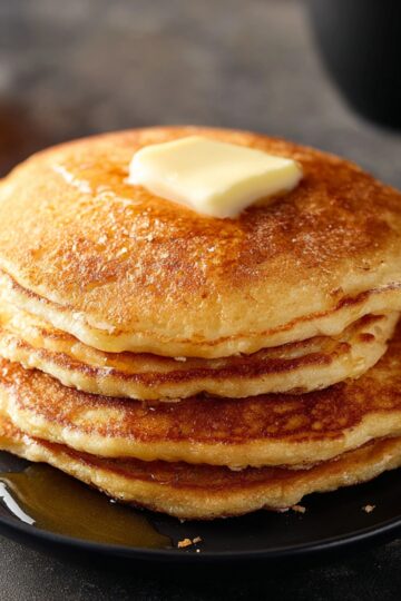 Delicious Sweet Potato Pancakes Recipe 3 sweet potato pancakes A stack of golden-brown pancakes served on a black plate, with melted butter and syrup on the side. The pancakes have a fluffy and light texture, showcasing a perfect breakfast setup.