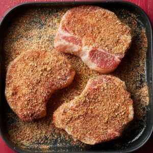 Raw pork chops covered with a flavorful seasoning mix, preparing for air frying.