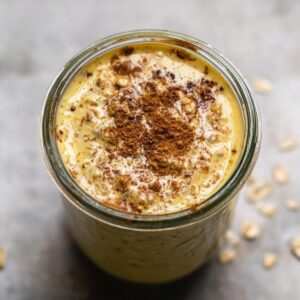 A jar filled with golden milk overnight oats, topped with a sprinkle of cinnamon and oats soaking in creamy milk.