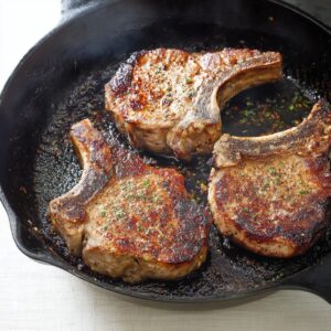 Easy Smothered Pork Chops Recipe 16 Perfectly seared pork chops resting in a hot skillet, caramelized to a beautiful brown on both sides, ready to be smothered with creamy gravy