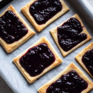 Healthy Blueberry Pop Tarts Recipe 15 Overhead shot of puff pastry rectangles on parchment paper, each filled with thick blueberry jam, raw pastry with clean edges, baking tray background, soft natural lighting, minimal styling, high detail, realistic food photography, 4k