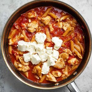 Best Buffalo Chicken Pasta Recipe 17 Chicken pieces in a skillet, with tomato sauce and a few dollops of cream cheese, ready to be mixed into the pasta
