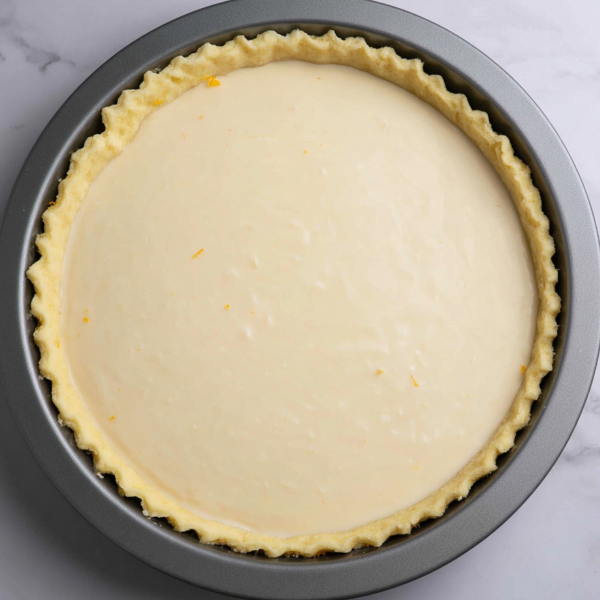Best Buttermilk Pie Recipe 12 A pre-baked buttermilk pie with a smooth, creamy filling inside a crimped pie crust. The edges of the pie crust are neatly folded, and the filling is still uncooked, awaiting baking.