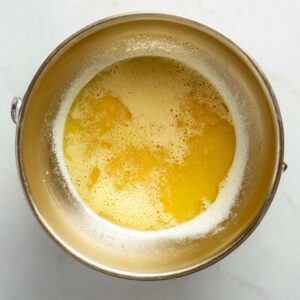 Best Buttermilk Pie Recipe 15 A bowl of melted butter and milk mixture, ready to be poured into the buttermilk pie filling. The golden liquid creates a smooth, creamy base for the pie.