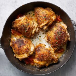 "Golden-brown chicken thighs seared in a skillet, creating a crispy outer layer before being added to the sauce for the chicken cacciatore.