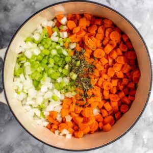 Healthy Chicken and Dumplings with Biscuits 14 A pot filled with diced carrots, celery, and onions, seasoned and ready to be added to the turkey and dumplings broth. These vegetables provide a fresh, aromatic base to the hearty dish.