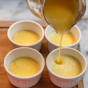 Healthy Chinese Steamed Eggs Recipe 15 Pouring the egg mixture into ramekins, likely as part of the preparation process before steaming.