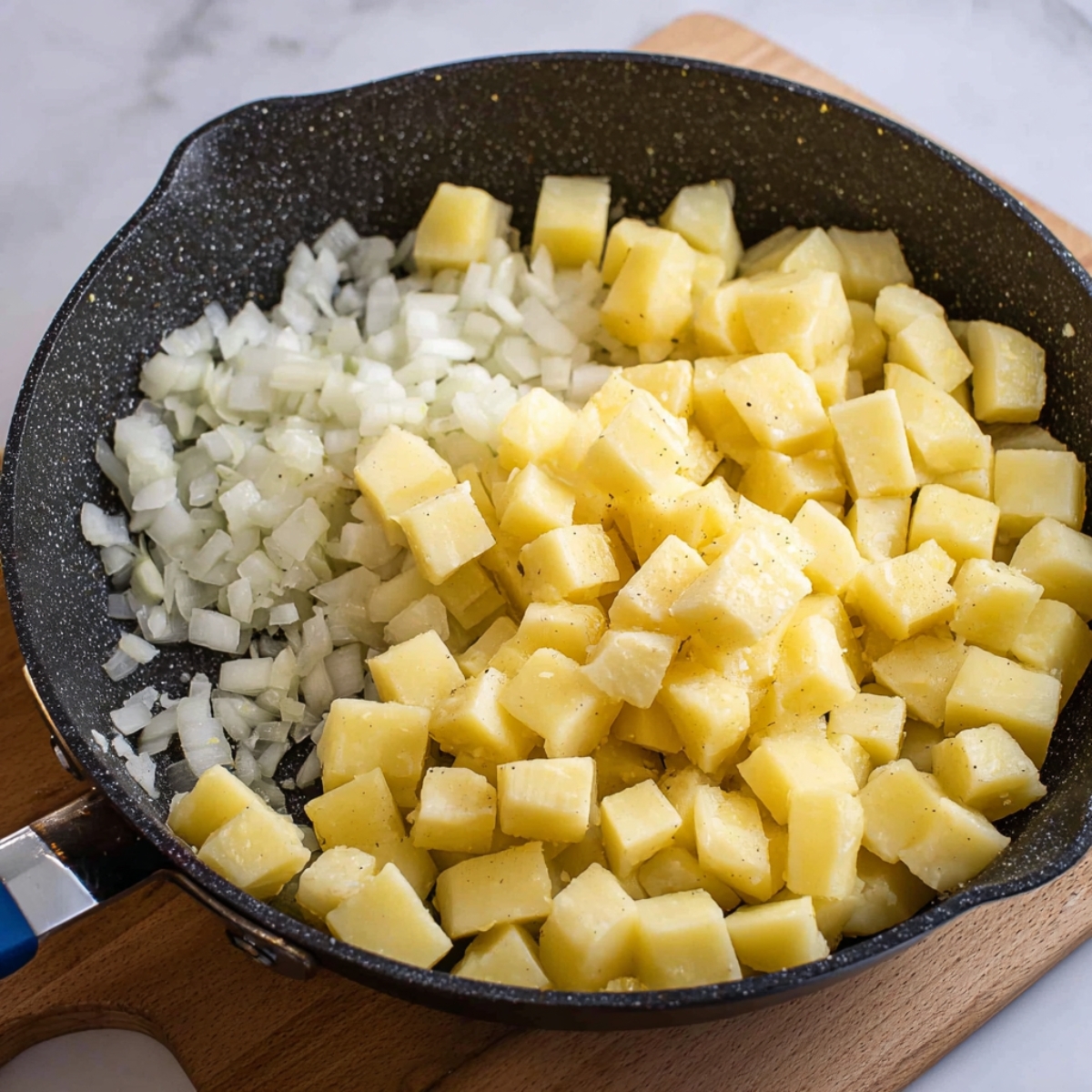 Easy Corned Beef Hash Recipe 12 Diced potatoes and onions in a pan, ready to be sautéed for corned beef hash.