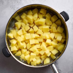 Easy Corned Beef Hash Recipe 15 Cubed potatoes boiling in a pot, ready to be added to the skillet for making corned beef hash