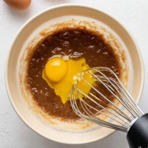 Easy Cosmic Brownies Recipe 15 Egg being added to the wet ingredients mixture for the brownie batter."