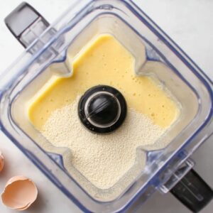 Blender filled with pancake batter ingredients, including eggs and flour