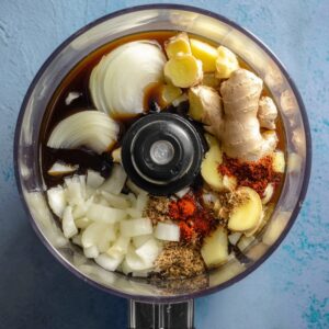 Best Homemade Ginger Dressing Recipe 13 A food processor filled with fresh ginger, onion, soy sauce, and spices, ready to be blended into a flavorful ginger dressing.