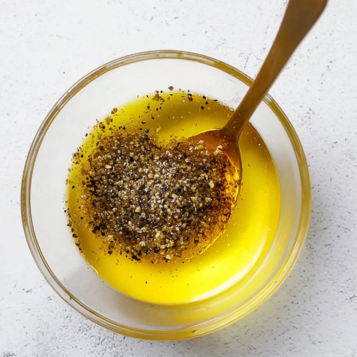 Delicious Grilled Salmon Recipe 10 A small glass bowl filled with olive oil, black pepper, and seasoning, ready to be brushed onto salmon for grilling