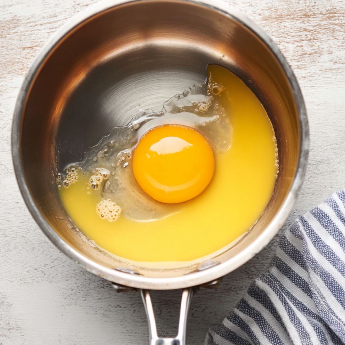 Easy Hollandaise Sauce Recipe 10 A fresh egg yolk and lemon juice in a saucepan, a key base for preparing hollandaise sauce.