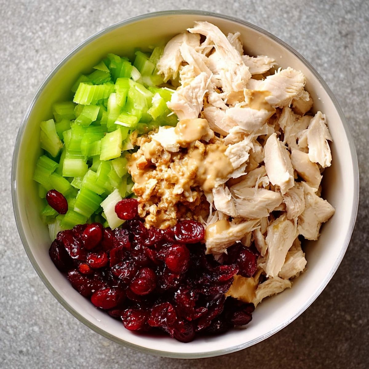 The Best Honey Mustard Chicken Salad Recipe 12 The second image shows the key ingredients—chicken, celery, and cranberries added to a bowl, ready to be mixed with dressing.
