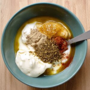 The Best Honey Mustard Chicken Salad Recipe 14 image shows the ingredients for the honey mustard dressing (such as yogurt, mustard, and seasonings) in a small bowl before being mixed together.