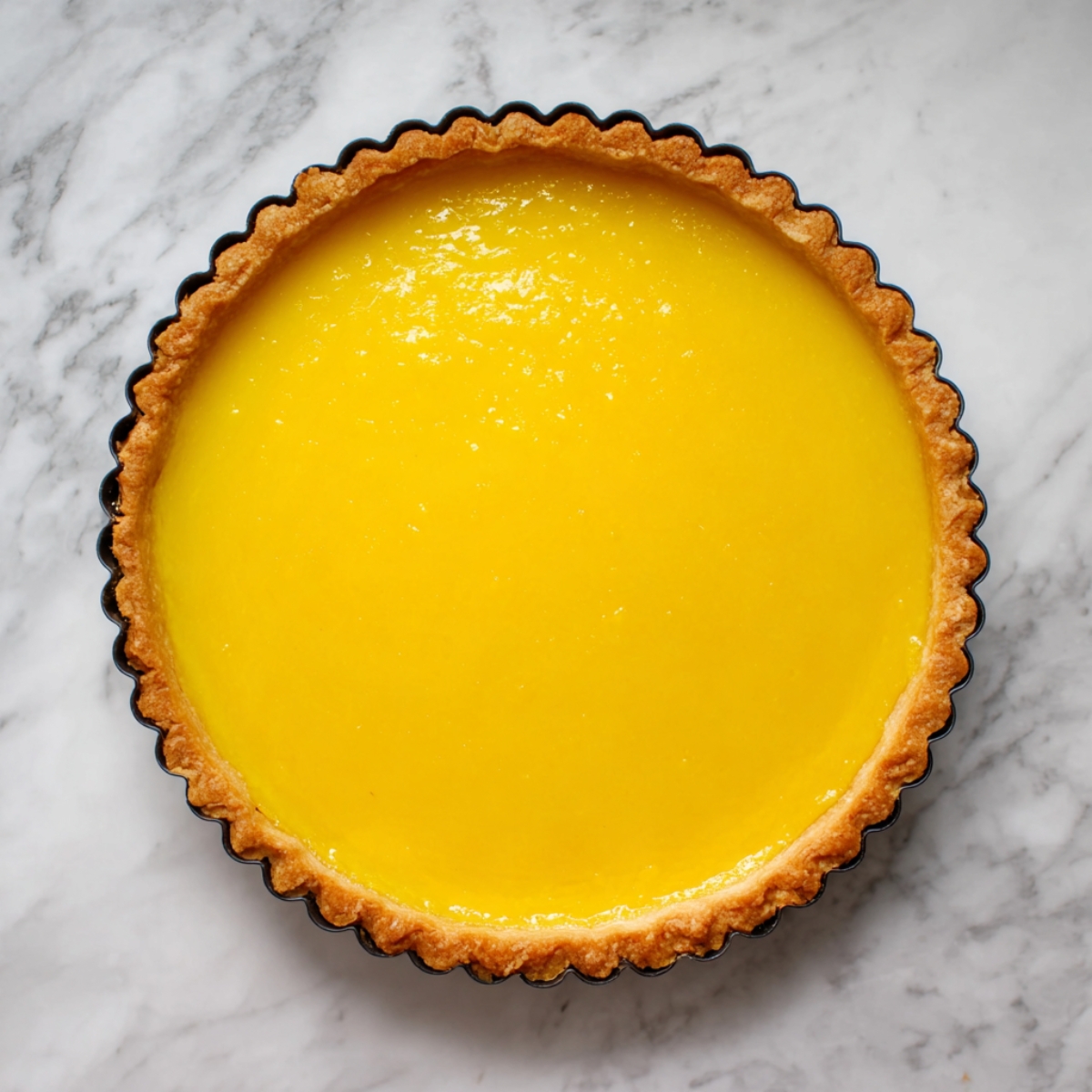 Easy Lemon Blueberry Tart Recipe 13 A freshly baked lemon tart, sitting on a marble surface. The bright yellow filling is smooth and glossy, encased in a golden, perfectly baked tart crust. The surface of the tart looks flawless and inviting.