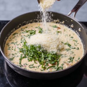 The finishing touches are added to the creamy sauce: fragrant fresh basil and a generous sprinkle of grated cheese. The herbs add a burst of freshness, while the cheese melts into the sauce, making it even richer and more indulgent.