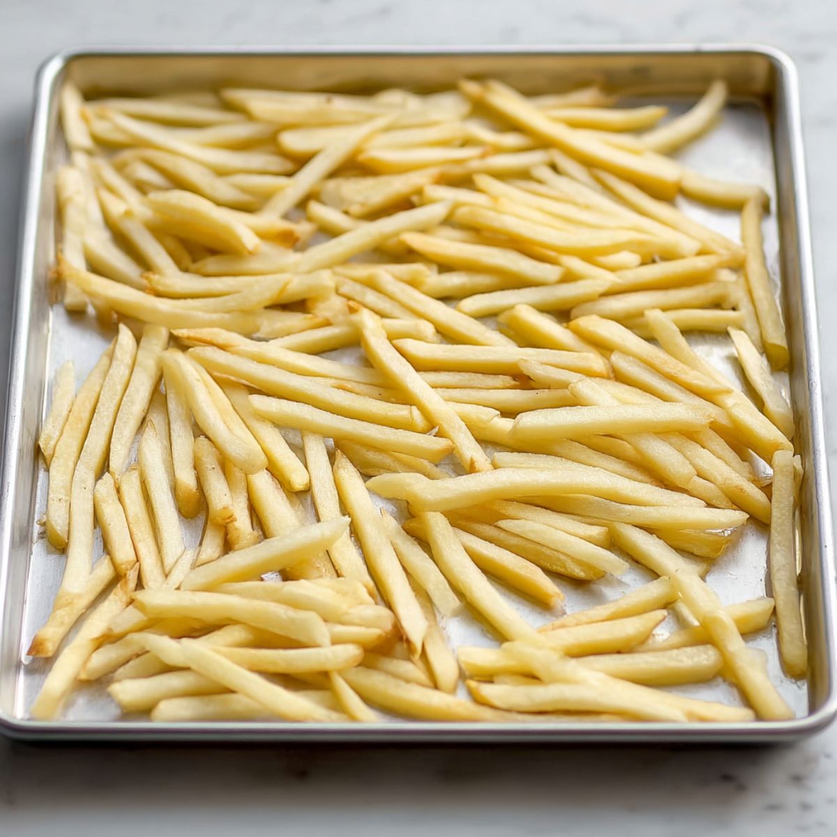 Delicious Poutine Recipe 11 Raw French fries arranged on a baking sheet, ready to be baked for a crispy, golden finish.