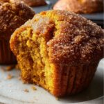 Pumpkin Muffins Close-up of a freshly baked pumpkin muffin with a cinnamon-sugar crust and a soft, moist interior on a white plate