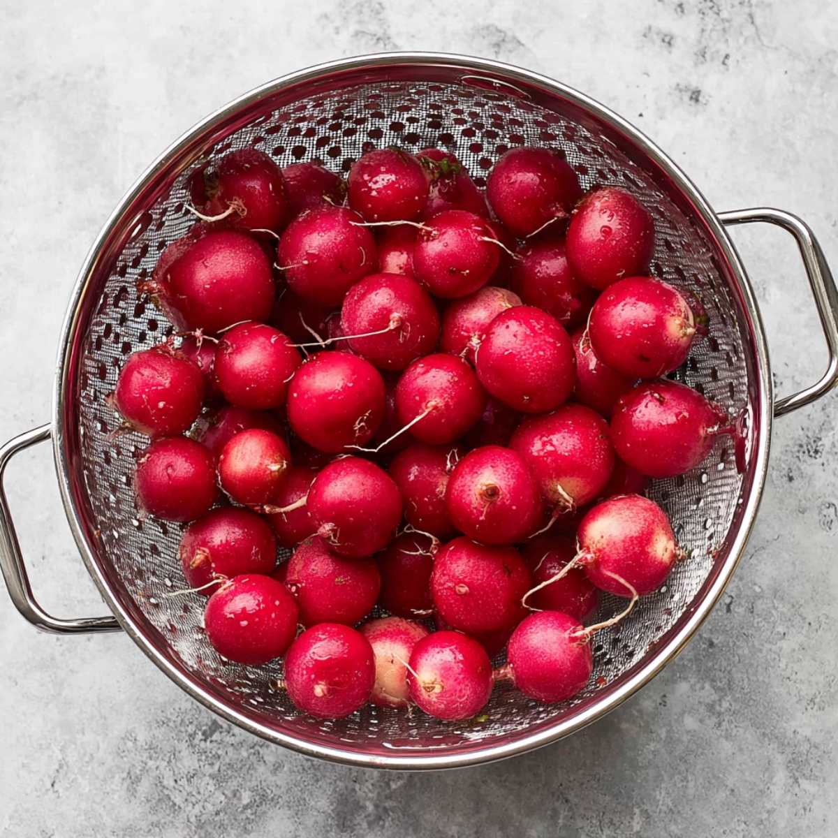 Easy Roasted Radishes Recipe 10 "A colander filled with fresh, unwashed radishes, showcasing their bright red skin. The radishes are clean and round, ready for the next step in the cooking process."