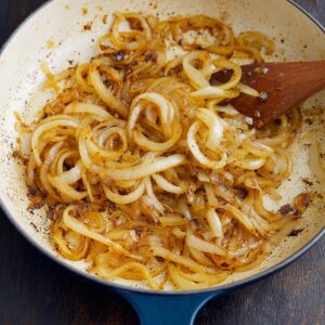 The Best Smothered Chicken Recipe 17 Sautéed onions in a pan, slowly caramelized to a golden color. The onions are soft and aromatic, adding depth to the cooking base for the dish.