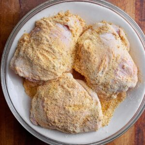 The Best Smothered Chicken Recipe 15 Chicken thighs coated with seasoned flour, ready to be cooked. The flour mixture ensures a crispy, golden crust once fried, adding texture and flavor to the chicken.