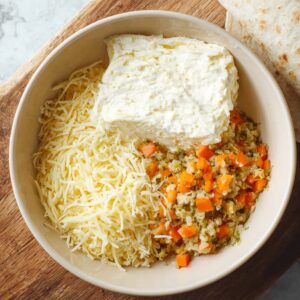 Easy Homemade Turkey Pinwheels Recipe 14 Mixing ingredients for the filling: "In a bowl, combine shredded cheese, cream cheese, vegetables, and seasonings to create a flavorful and creamy filling for the pinwheels."