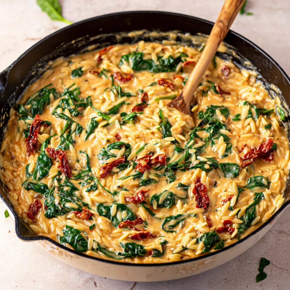Healthy Tuscan Chicken Orzo Recipe 13 A creamy skillet with orzo pasta, spinach, and sun-dried tomatoes mixed together. The dish has a smooth, rich sauce, and the spinach is wilted, creating a vibrant, comforting one-pan meal.