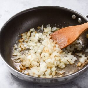 Delicious Grilled Chicken Burgers Recipe 15 Onions are being sautéed in a pan, adding a soft, caramelized texture and rich flavor that can be used as a topping or mixed into the burger patty.
