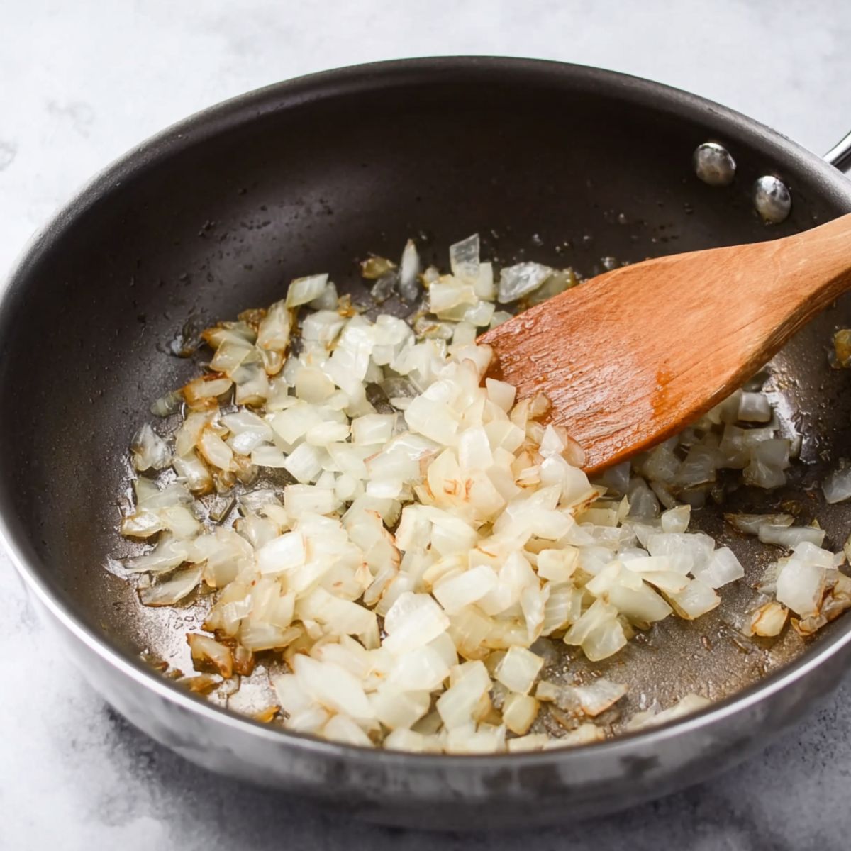 Delicious Grilled Chicken Burgers Recipe 10 Onions are being sautéed in a pan, adding a soft, caramelized texture and rich flavor that can be used as a topping or mixed into the burger patty.