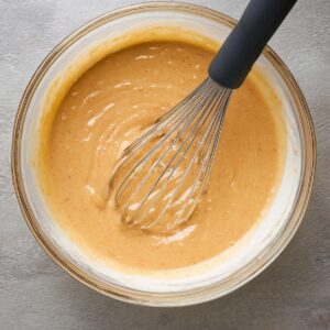 Delicious Sweet Potato Pancakes Recipe 17 A bowl of pancake batter, likely sweet potato-based, with a whisk inside. The batter has a smooth consistency and is ready for cooking.