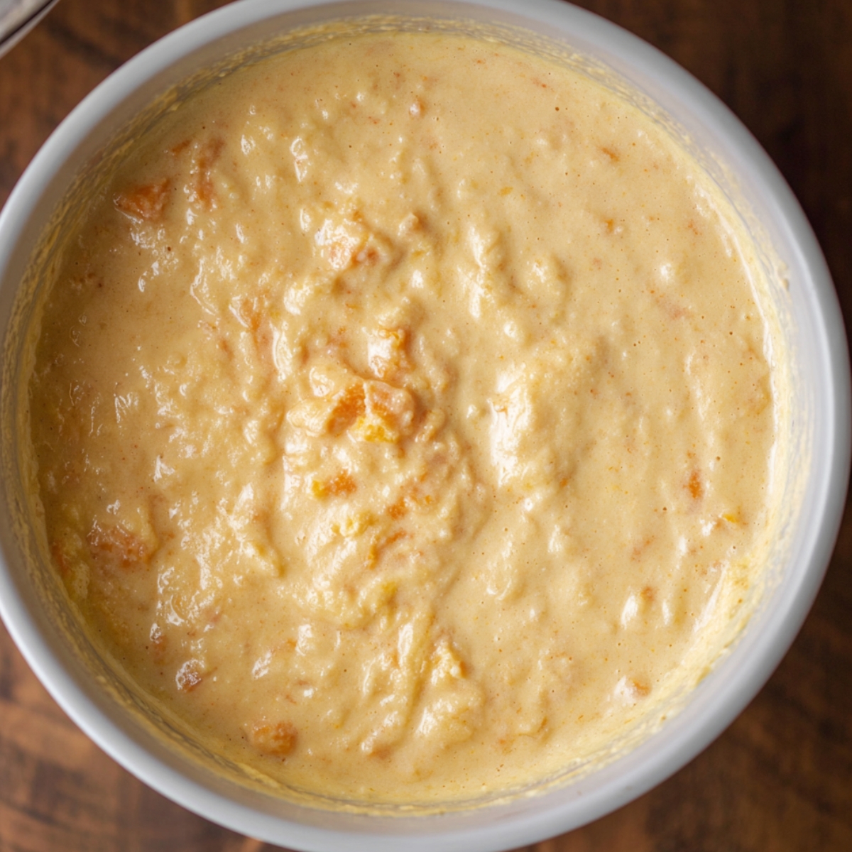 Delicious Sweet Potato Pancakes Recipe 11 A close-up of a creamy, textured liquid mixture in a bowl, likely a batter for pancakes or a similar baked good. It contains lumps of sweet potato, indicating that this is the beginning stage of a sweet potato-based recipe.