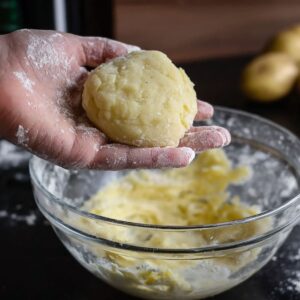 A hand holding a ball of mashed potato dough for potato cheese pancakes
