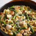 Chicken Asparagus Pasta Finished dish of chicken and asparagus pasta in a creamy sauce, garnished with grated cheese and ready to serve.