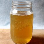 Chicken Broth A mason jar filled with a light golden-colored liquid, likely a homemade broth or stock