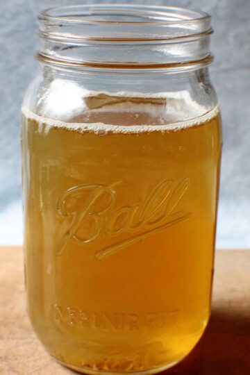 Best Chicken Broth Recipe 2 Chicken Broth A mason jar filled with a light golden-colored liquid, likely a homemade broth or stock