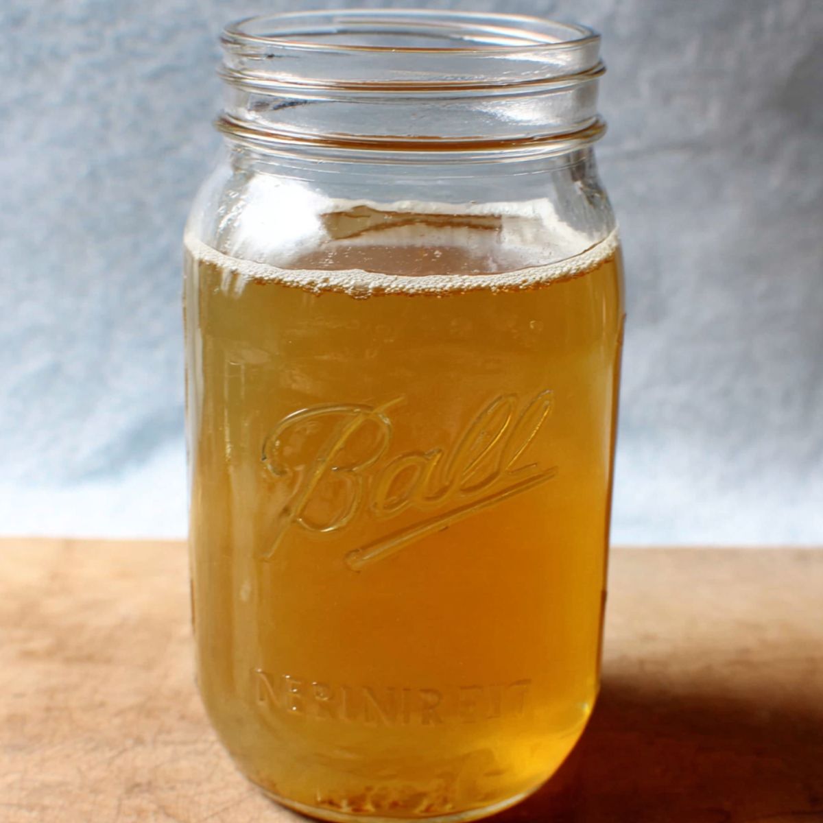 Chicken Broth A mason jar filled with a light golden-colored liquid, likely a homemade broth or stock